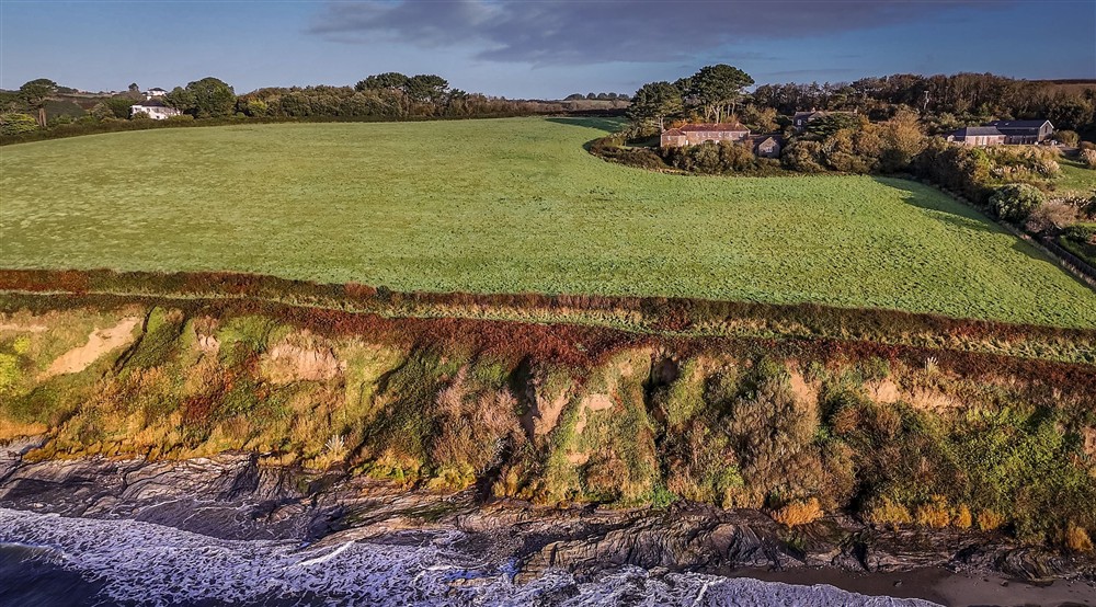 An aerial view of the Gwendra cottages on the cliff above Pendower beach at Mowhay in Truro, Cornwall