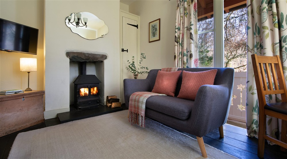 The sitting room with woodburning stove and glass doors onto the veranda at Nant Las in Dolgellau, Gwynedd