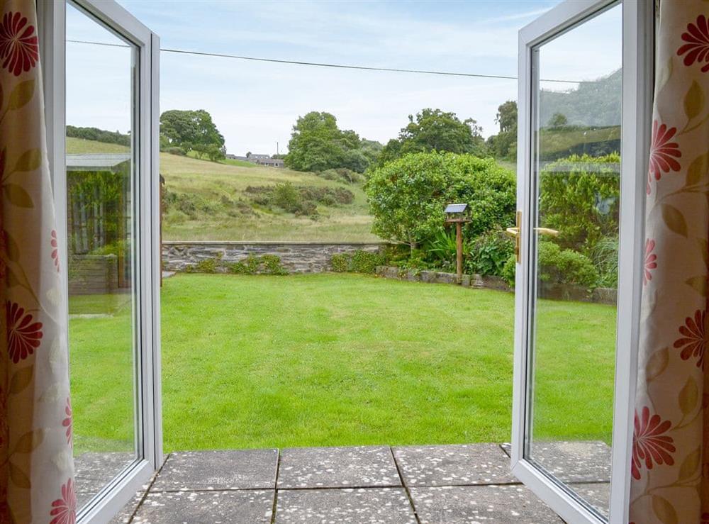 Patio doors lead directly to the private garden and summerhouse with table and chairs at Nant y Bwthyn in Dol-y-Bont, near Borth, Cardigan-Ceredigion, Dyfed