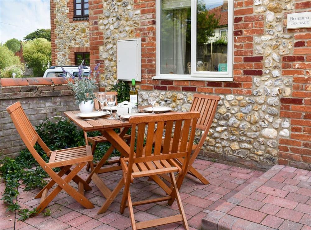 Small, enclosed, paved courtyard with garden furniture at Bluebell Cottage, 