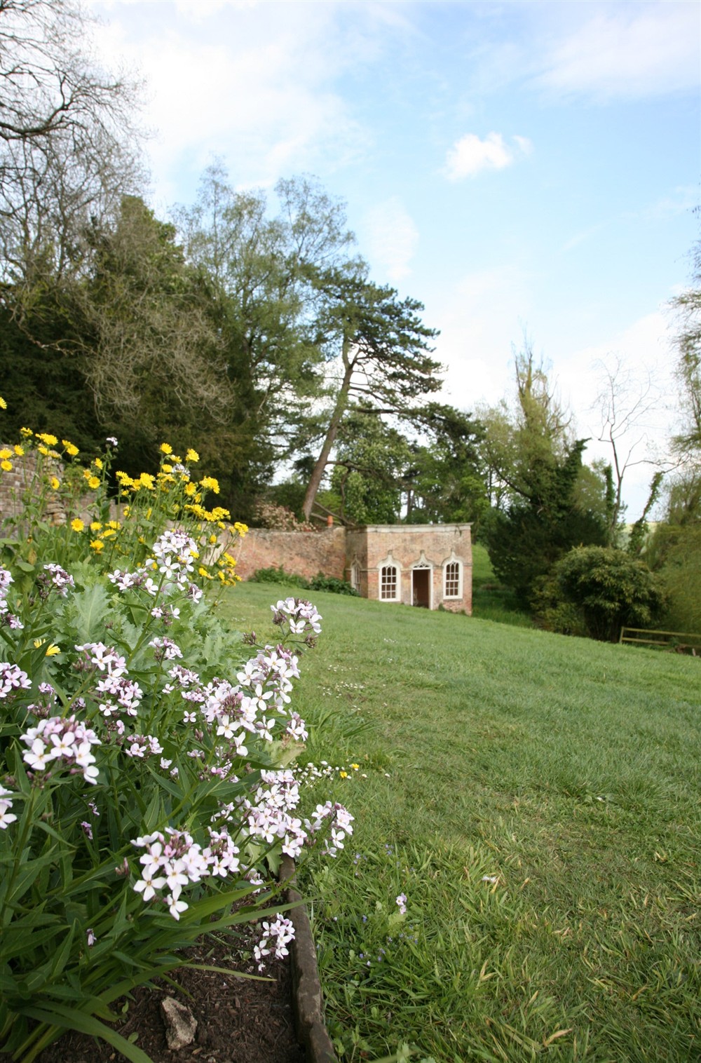 A border in bloom next to the green bank leading to the Summerhouse at Newark Lower Lodge in Wotton-under-edge, Gloucestershire