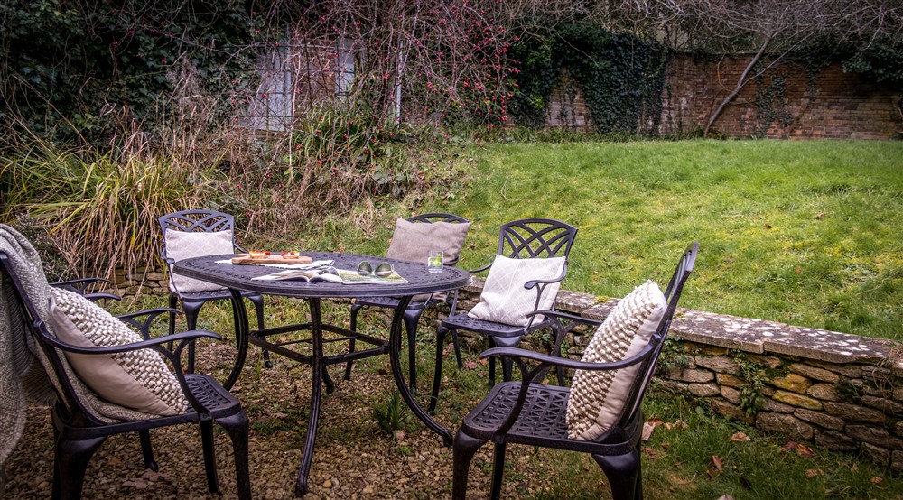 The enclosed rear garden, with dining furniture and lawn, at Newark Lower Lodge in Wotton-under-edge, Gloucestershire