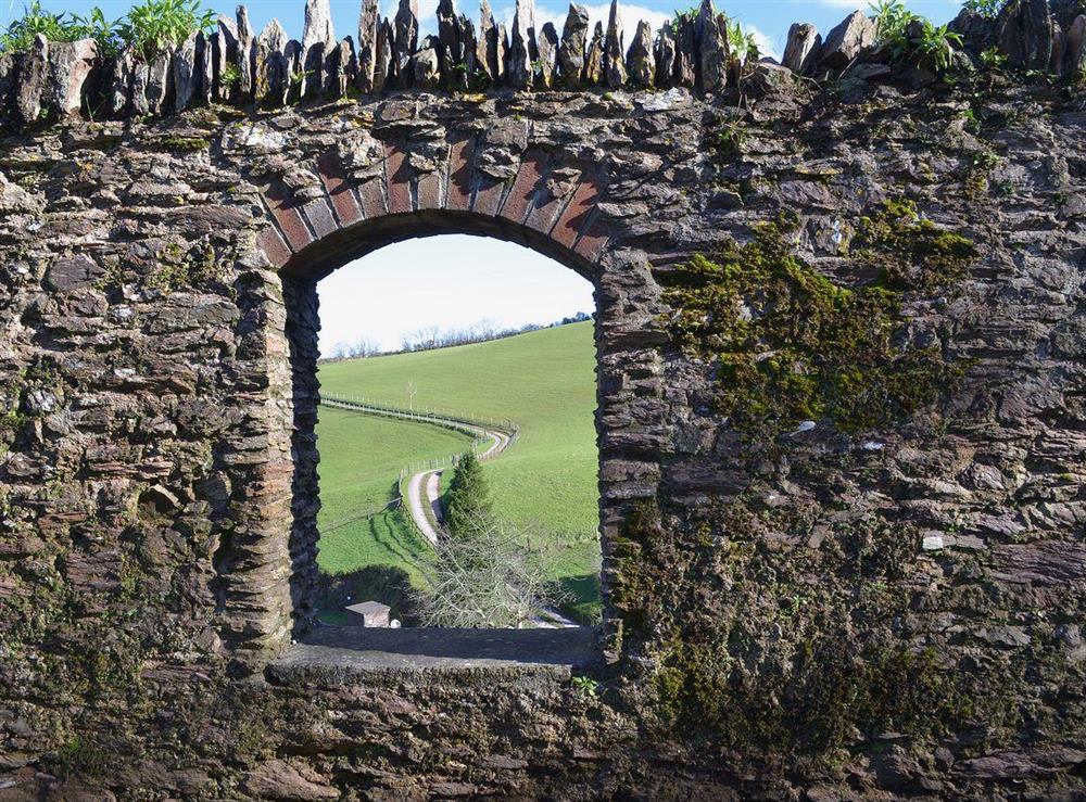 A meandering single track road glimpsed through one of the stone arches in the grounds at Anglers Rest, 