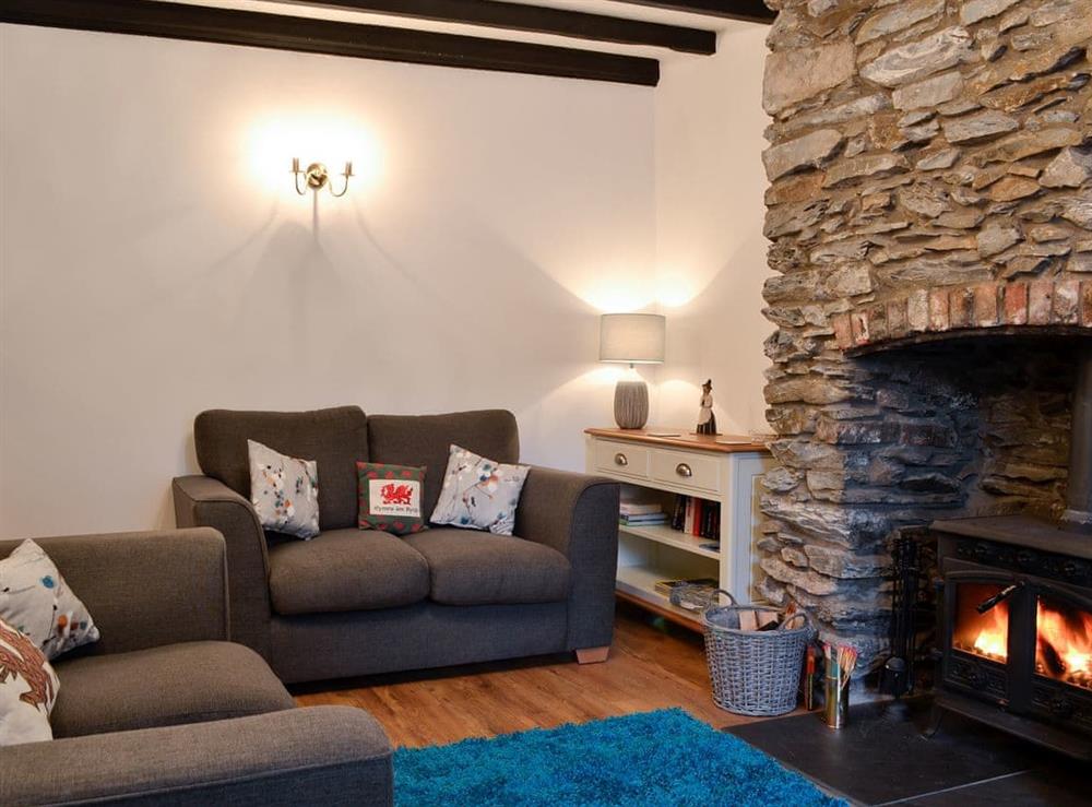 Beamed living room with exposed stone chimney breast at Noddfa Cottage in Llanfairtalhaiarn, near Abergele, Clwyd