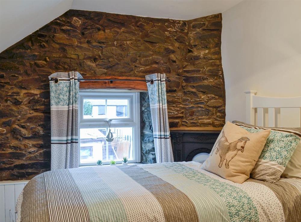 Bedroom with exposed stone wall at Noddfa Cottage in Llanfairtalhaiarn, near Abergele, Clwyd