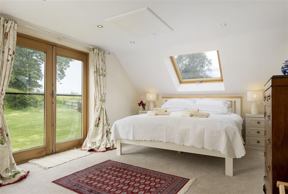First floor: Bedroom one with 6ft super-king size bed, television and en-suite bathroom at North Leigh Barn, Crediton
