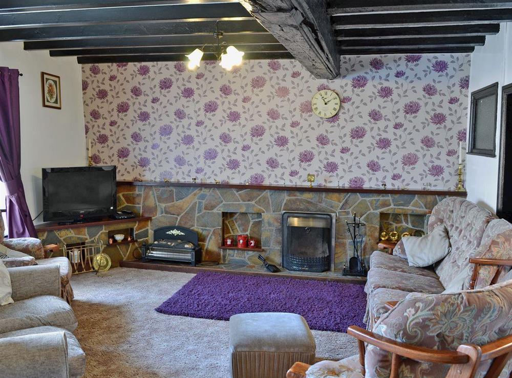Living room full of character with open fire and beams at Nyffryn Bella in Nefyn, near Pwllheli, Gwynedd