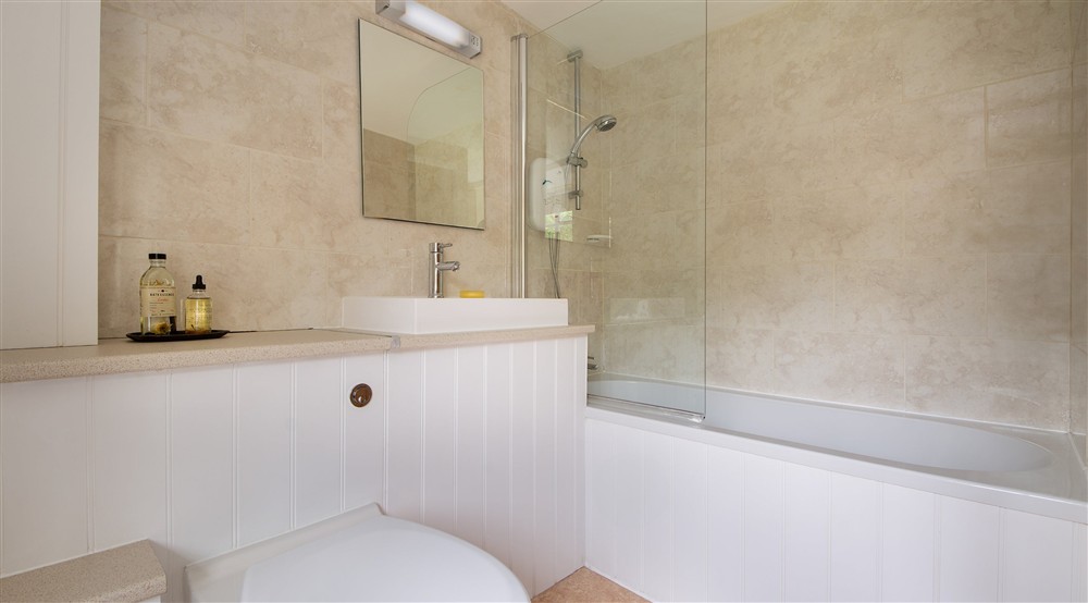 The en-suite bathroom with shower over bath at Oak Cottage in Bridport, Dorset