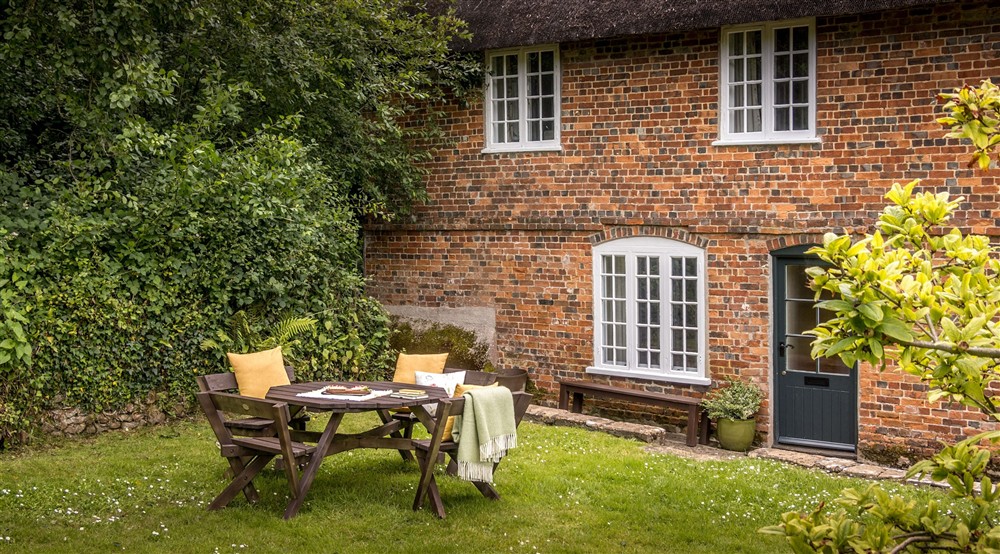 The exterior of Ash Cottage and its picnic table in the shared garden, Dorset at Oak Cottage in Bridport, Dorset