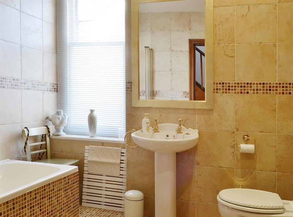 The fully tiled bathroom has a heated towel rail and a shower over the bath at Oak Lea in Keswick, Cumbria