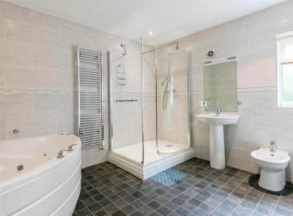 Bathroom with jacuzzi bath, shower cubicle and toilet at Oaklands in Langrigg, near Cockermouth, Cumbria