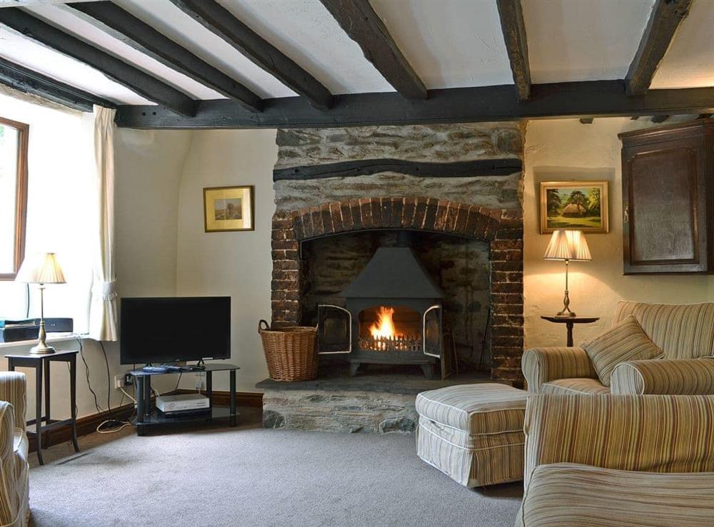 Characterful living room with beams and wood-burning stove at Oaks Farm Cottage in Ambleside, Cumbria., Great Britain