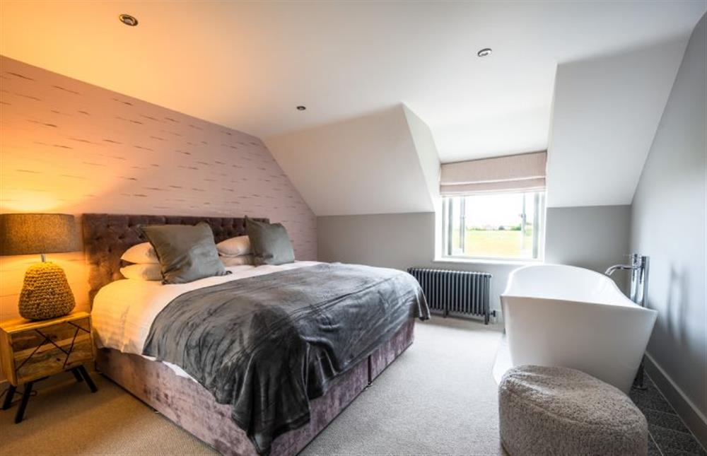 First floor: Bedroom three, super-king bed and freestanding bath at Old Farm, Thornham near Hunstanton