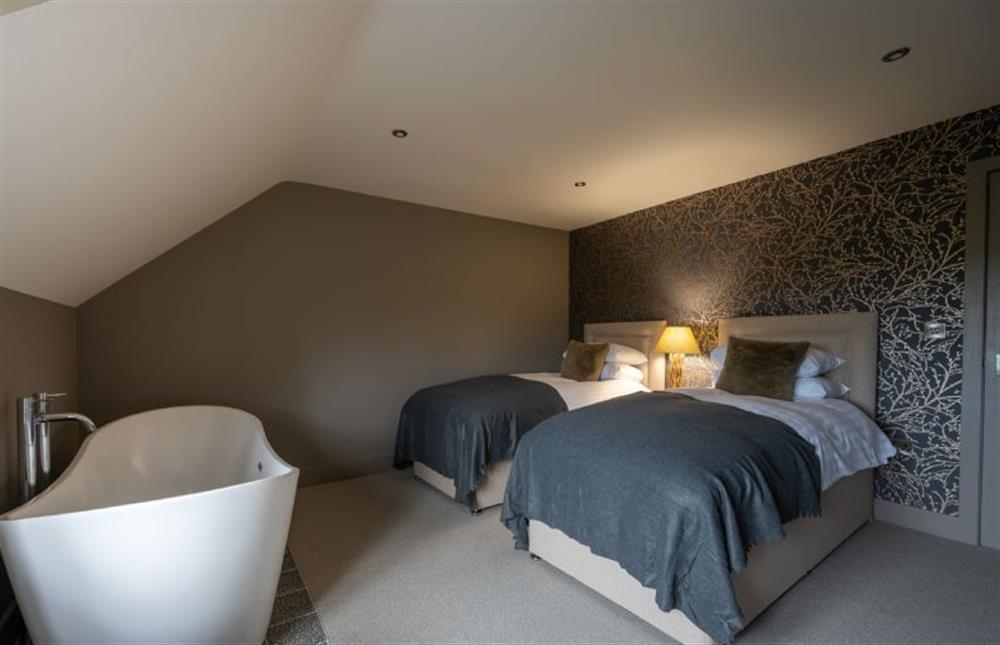 First floor: Bedroom two has twin beds, sea views and a freestanding bath at Old Farm, Thornham near Hunstanton