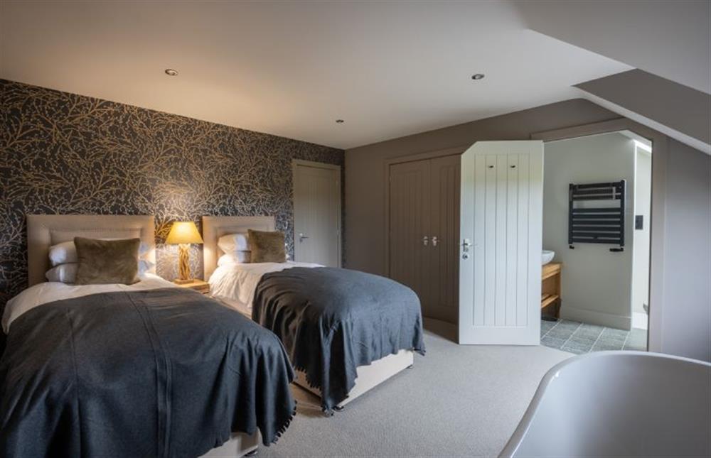 First floor: Bedroom two with twin beds and freestanding bath at Old Farm, Thornham near Hunstanton