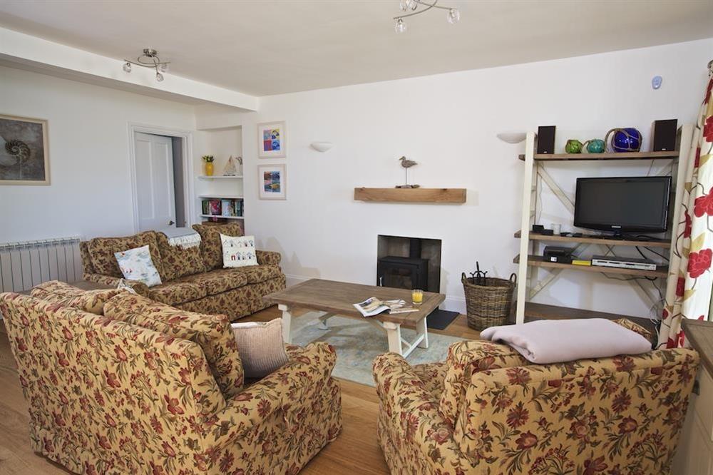 A bright well proportioned sitting room comfortably furnished with two large sofas and matching armchair