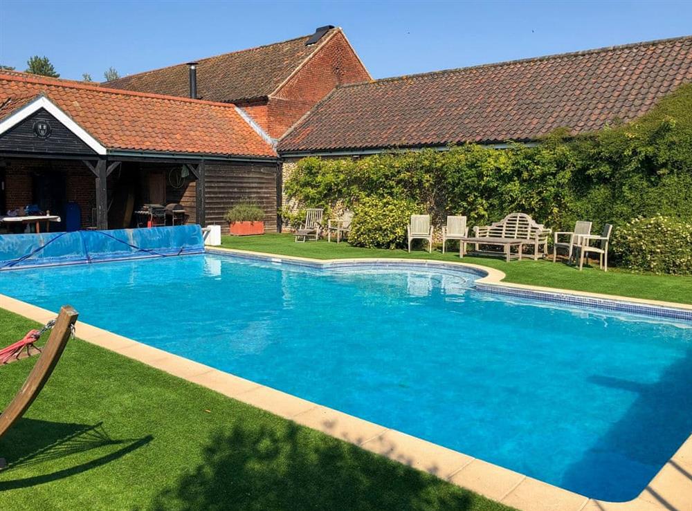 Shared outdoor heated swimming pool at Orchard House in Hempstead, near Holt, Norfolk
