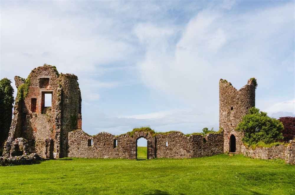 The old Crom castle ruins break up the horizon standing against a clear blue sky at Orchard View in County Fermanagh,
