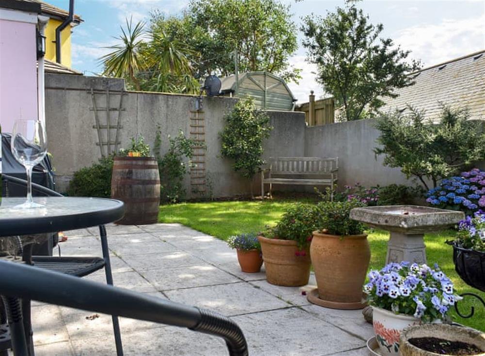 Enclosed lawned garden with patio and garden furniture at Our Retreat in Kingsbridge, Devon
