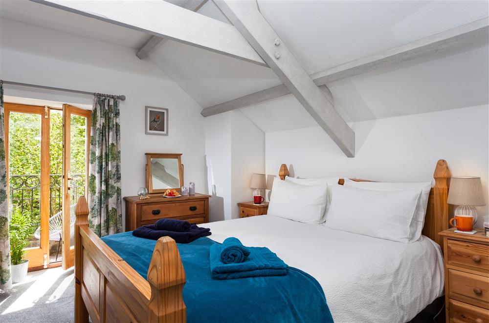 Bedroom one with a 5’ king-size bed and doors leading to the balcony at Owl Cottage, Llanwrda