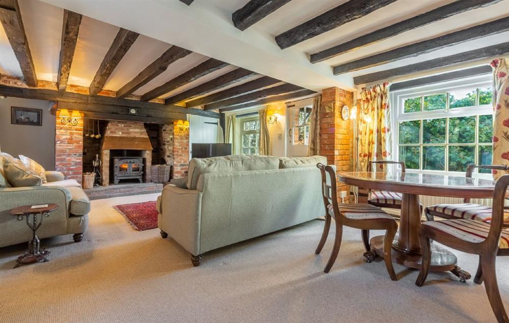 Sitting room with wood burning stove and dining table at Peak Hill Cottage, Theberton