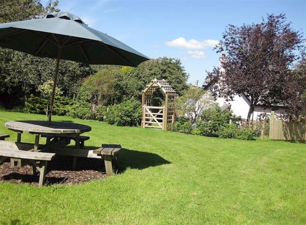A thoughtfully placed outdoor eating area taking advantage of the large lawned garden at Peartree Cottage in 
