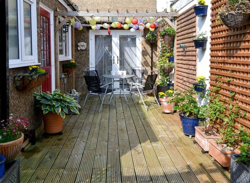 Enclosed lawned garden with terrace area and garden furniture at Pebble Cottage in Caister-on-Sea, Norfolk