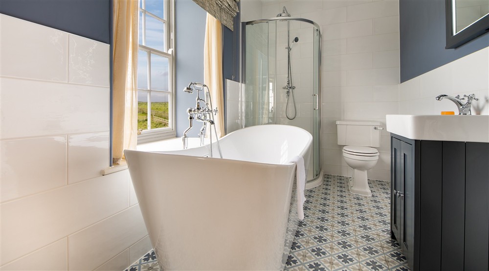 The en-suite bathroom, with freestanding bath and walk-in shower, to the first double bedroom at Pengirt in Polzeath, Cornwall
