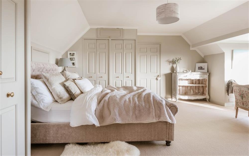 Master bedroom with a king-size bed, fitted wardrobes and a door leading into the twin room. at Penmorva in Helford Passage