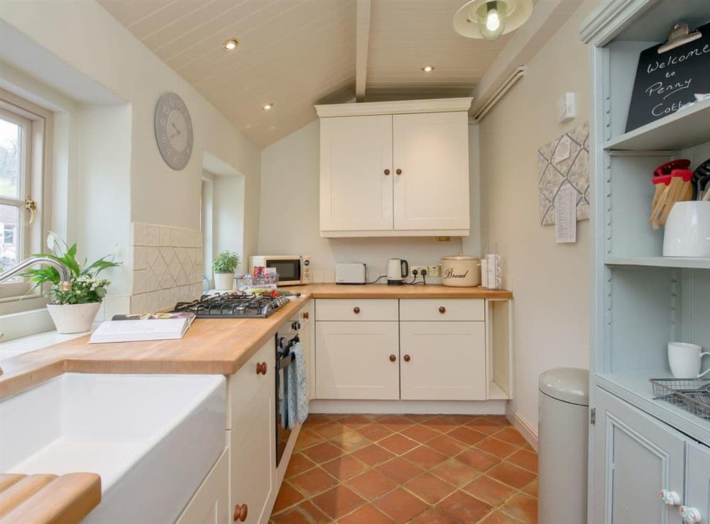 Galley-style kitchen with quarry-tiled floor at Penny Cottage in Bonsall, near Matlock, Derbyshire