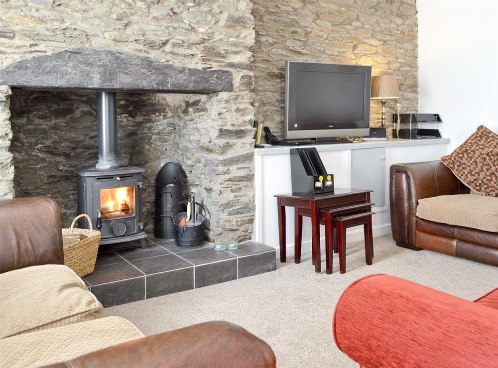 Stylish living room with wood burner and exposed stone feature wall at Penteryfn in near Holyhead, Isle of Anglesey, Gwynedd