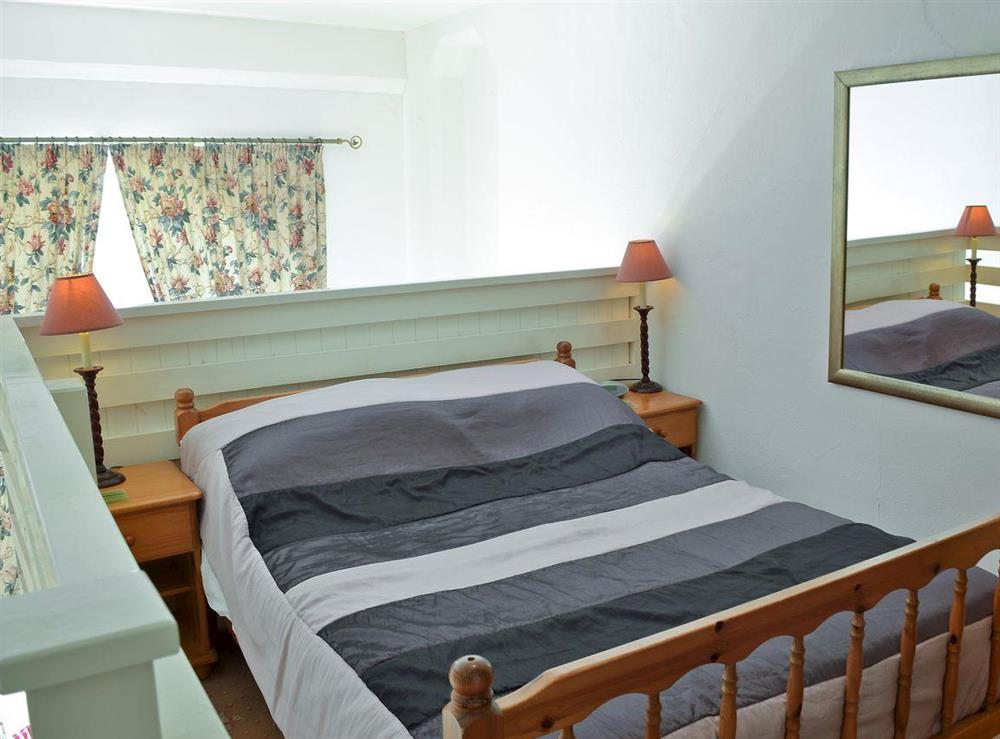 Galleried bedroom with double bed and en-suite with shower cubicle and toilet at Cloisters Cottage, 