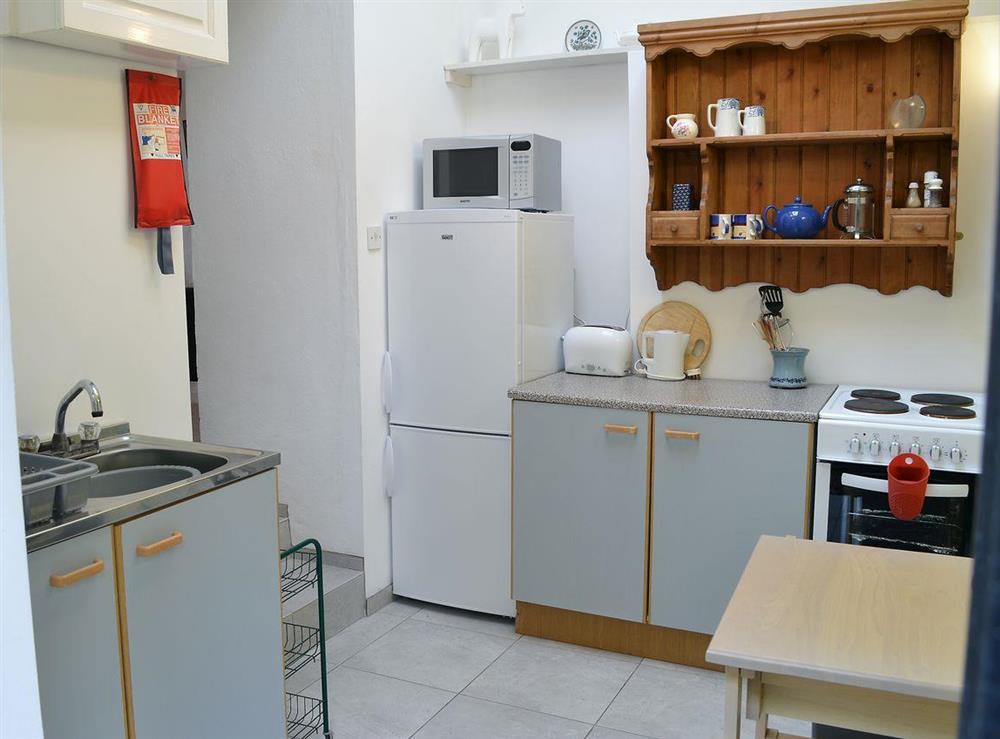 Kitchen area with electric cooker, microwave, fridge and freezer at Cloisters Cottage, 