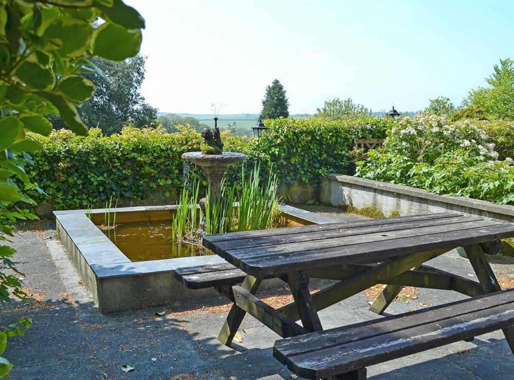 Outdoor dining area and unfenced pond within grounds at Stable Cottage, 