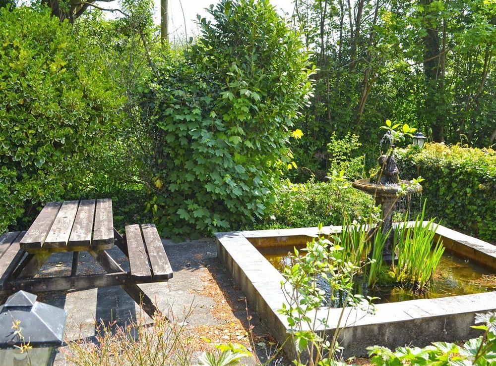 Delightful outdoor sitting area with pond (unfenced) within grounds at Stable End, 