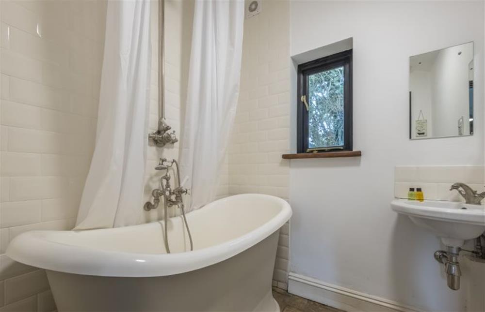 Bathroom with a roll-top bath with shower over and wash basin at Pettingalls Farm Cottage, Deopham Green near Wymondham