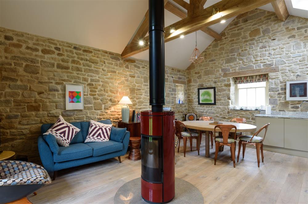 The open-plan kitchen, dining and sitting area with central wood burning stove at Pingle Cottage, Chatsworth Estate, Nr Matlock 