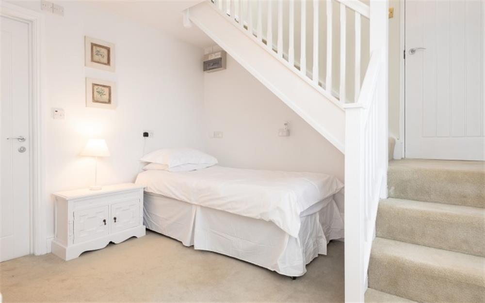 The single bed in alcove under the stairs
