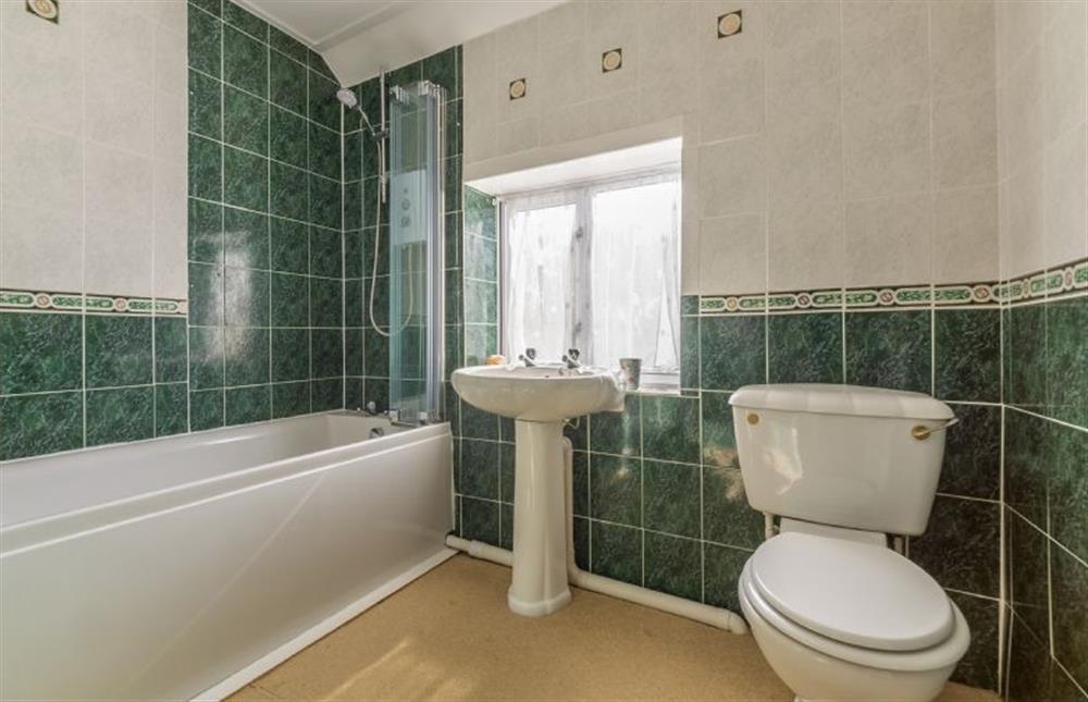 First floor: Family bathroom has bath with shower over at Plunketts Cottage, Brancaster near Kings Lynn