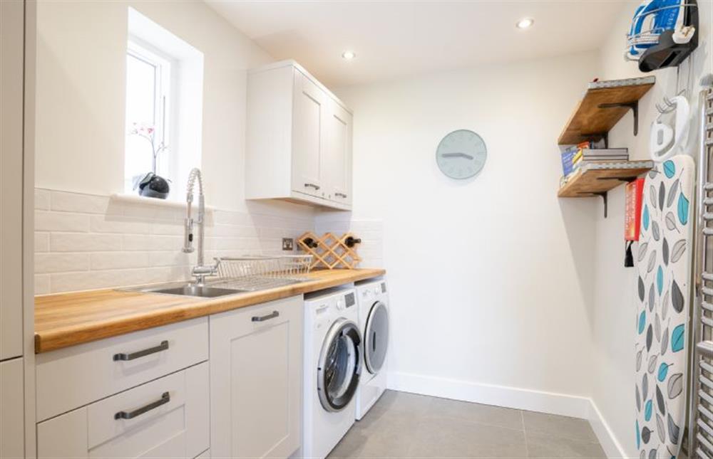 Utility room with a washing machine, tumble dryer, clothes airer, iron and ironing board at Polberro Cottage, St Agnes