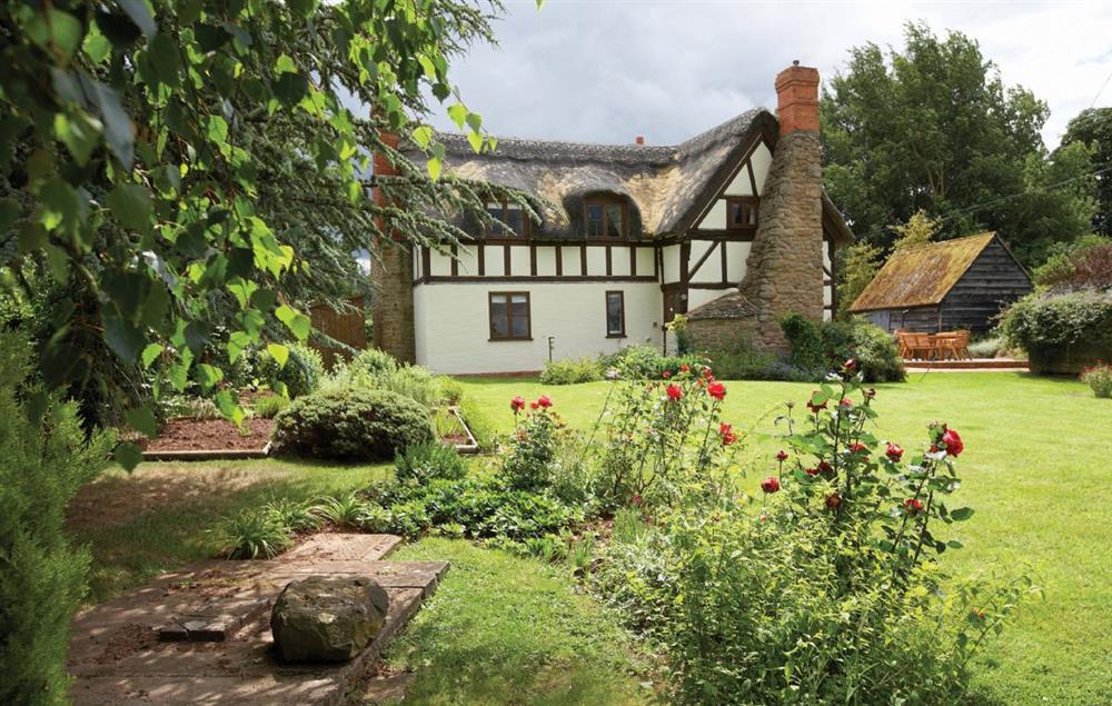 Beautiful rear garden with decked seating area at Pool Head Cottage, Westhide