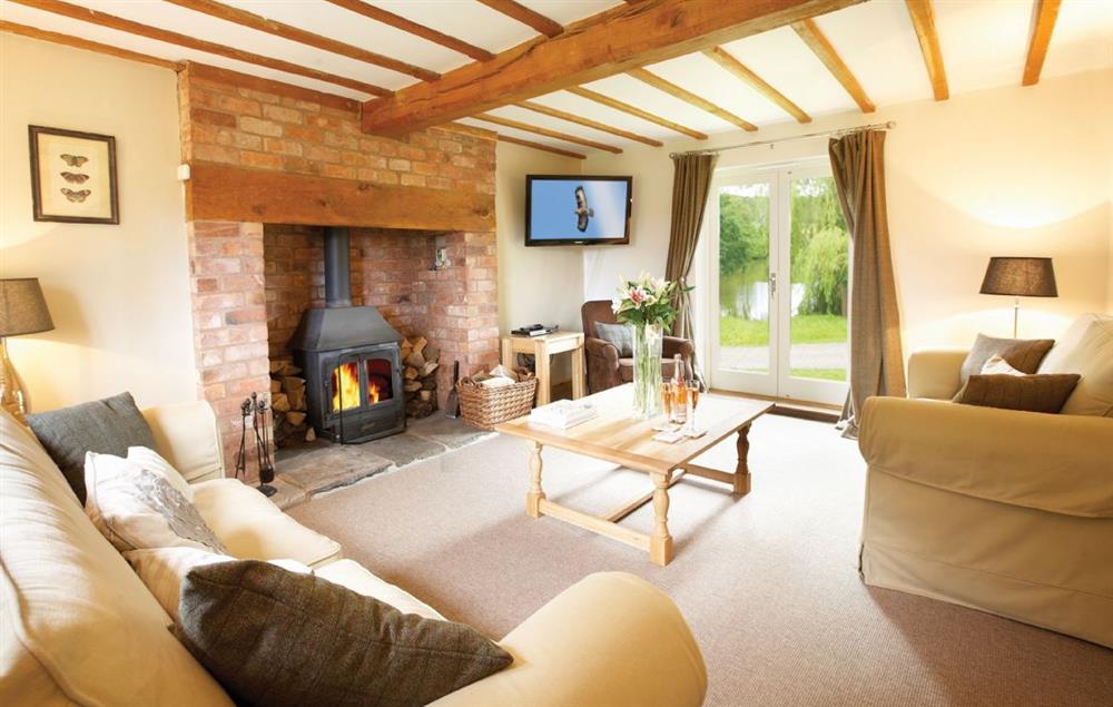 Large sitting room wood burning stove and French windows which open onto the front garden at Pool Head Cottage, Westhide