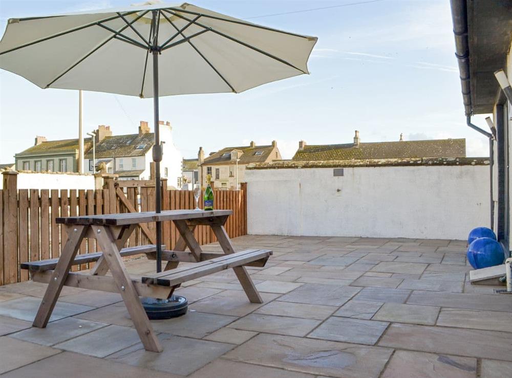 Paved patio area with outdoor furniture at Porthole Cottage in Allonby, near Maryport, Cumbria