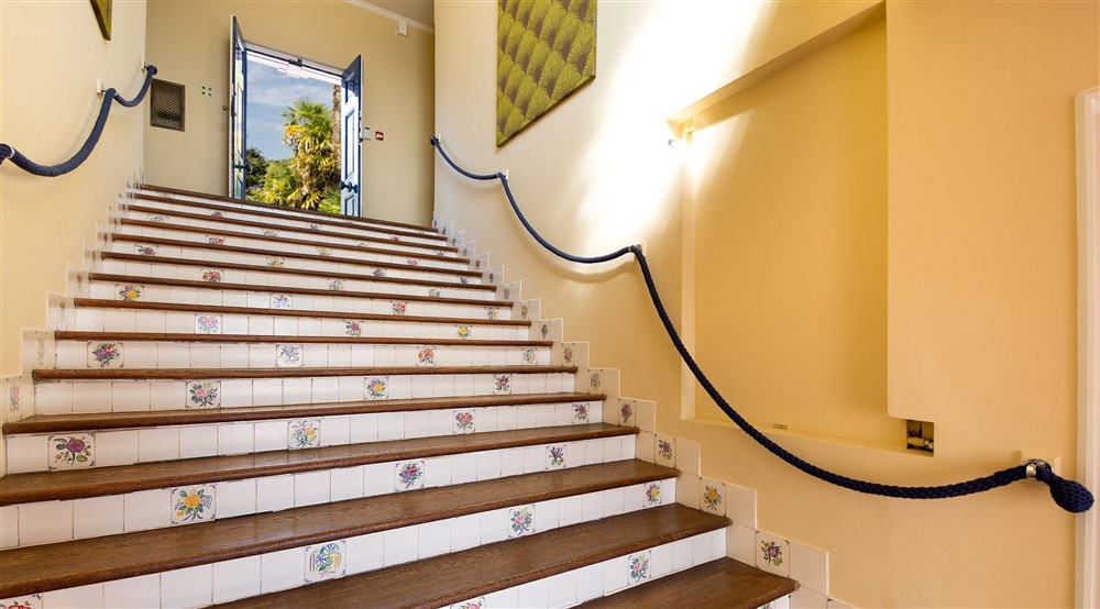 Looking up the main staircase, with rope banisters and period Poole Pottery tiles with floral designs. It leads to the main entrance door on the first floor of Portland House, Dorset at Portland House in Weymouth, Dorset