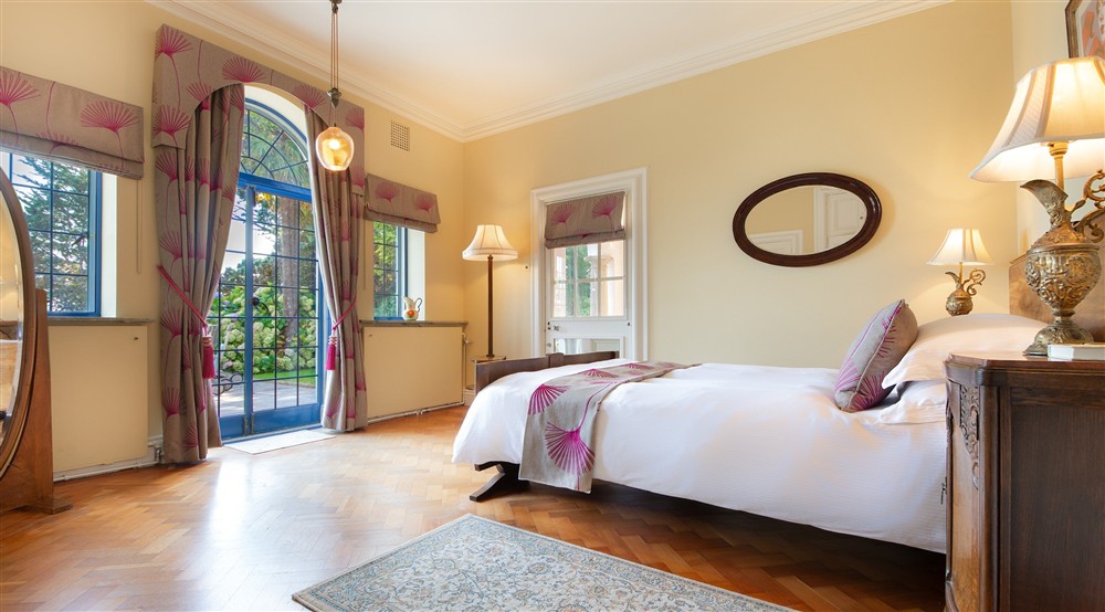 One of the double bedrooms on the ground floor, with a connecting door to the next double bedroom and external door to the lower terrace and covered loggia at Portland House in Weymouth, Dorset