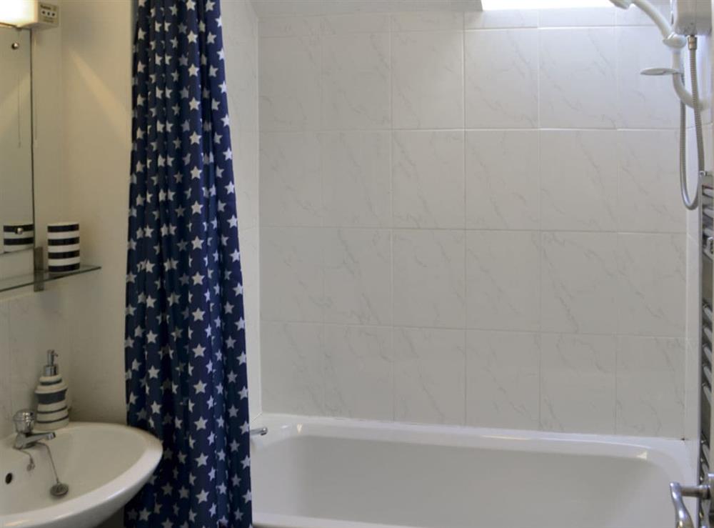 Bathroom with shower over bath and heated towel rail at Pottergate Cottage in Wroxham, Norfolk
