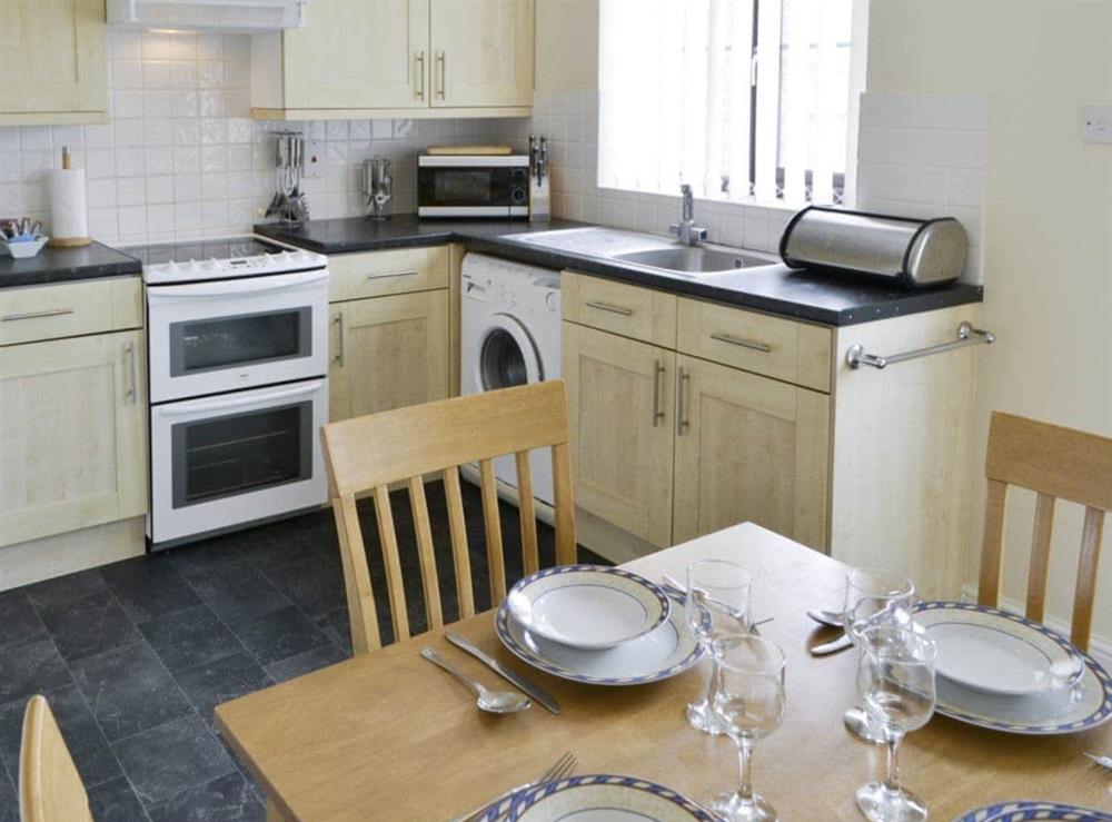 Well-equipped fitted kitchen with dining area at Primrose Cottage in Sea Palling, Norfolk