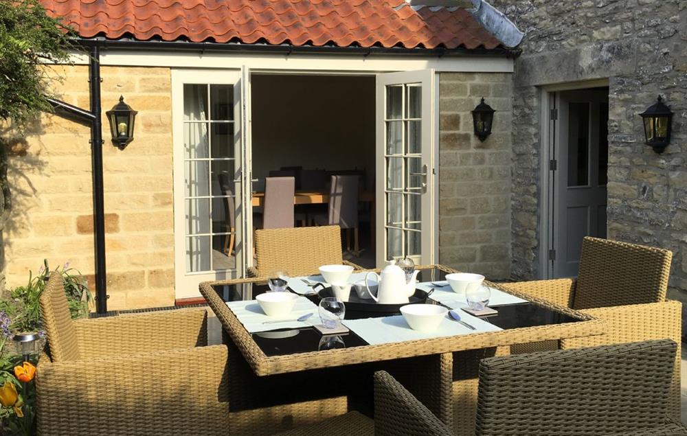 French doors from the dining room lead on to a paved patio with garden furniture at Prospect House, Ampleforth