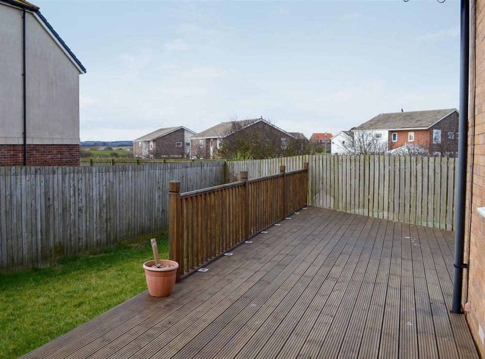 Enclosed lawned garden with decked area and garden furniture at Puffin Place in Beadnell, near Alnwick, Northumberland