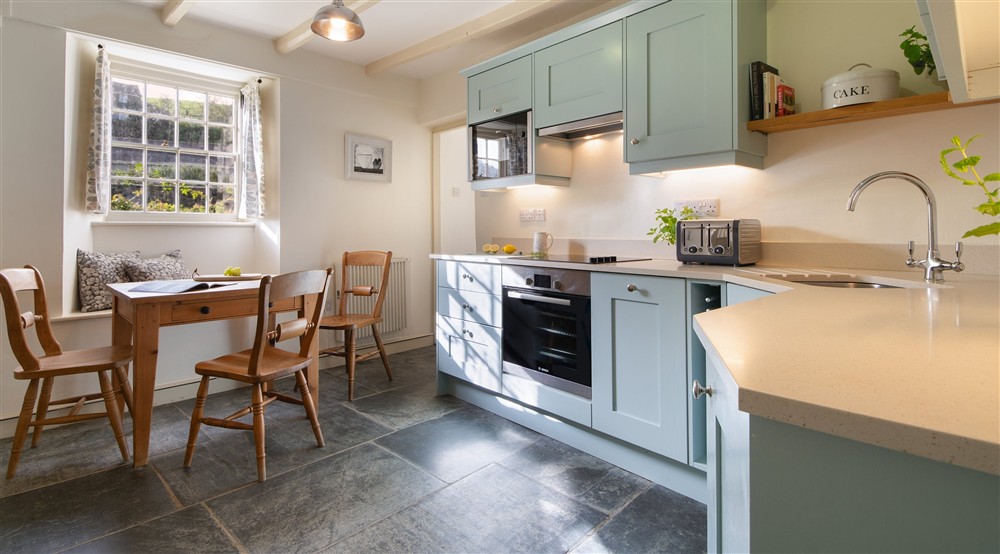 The kitchen with a table for three at Quin Cottage in Port Quin, Cornwall